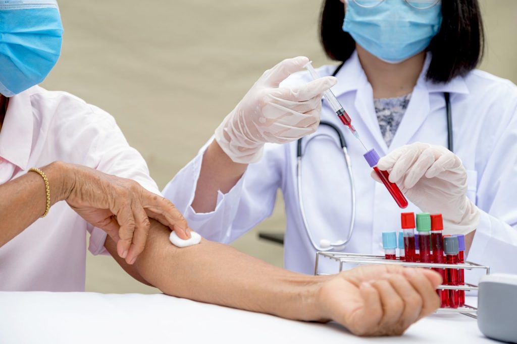 A doctor collecting a blood sample from a patient into a test tube