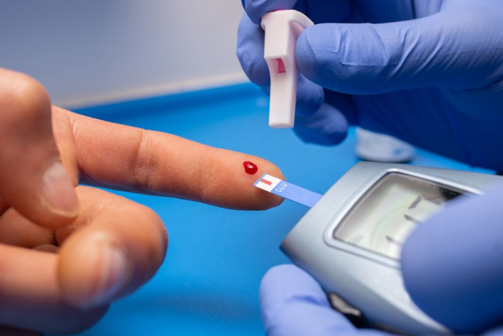 A finger-prick blood sample being read on a glucose testing device